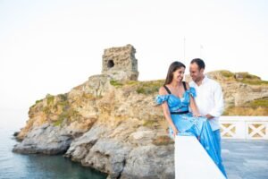 Romantic pre-wedding portrait of a couple in Chora, Andros, with the historic Venetian Kato Kastro and the Aegean Sea in the background.
